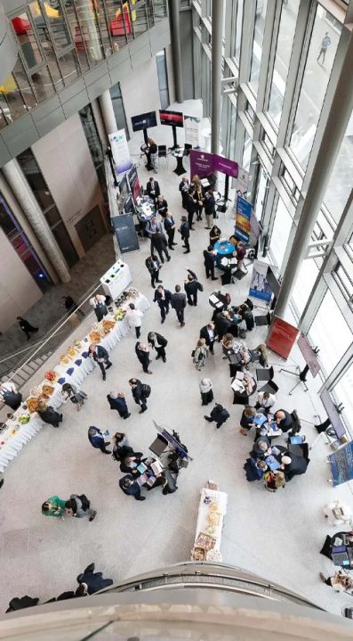 downwards facing view of people in suits walking around foyer of trinity business school