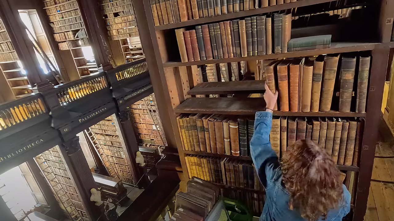 person removing an old book from a shelf