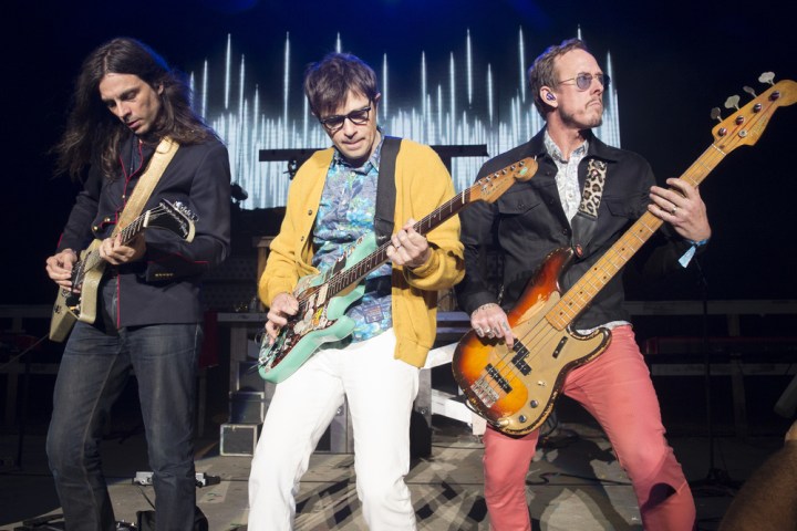 3 musicians from Weezer on stage playing guitars