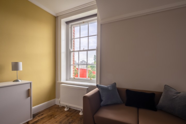 Couch with a cushion and a large window with a view in an apartment