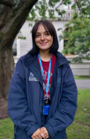 Tour guide smiling on front of a tree on Trinity campus