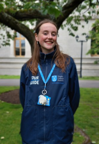 Tour guide smiling on front of a tree at Trinity