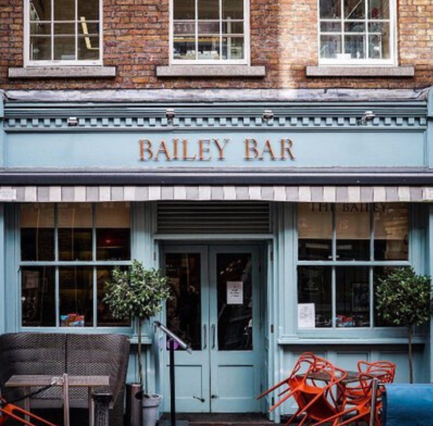 The front of a bar with blue wooden beams under brickwork