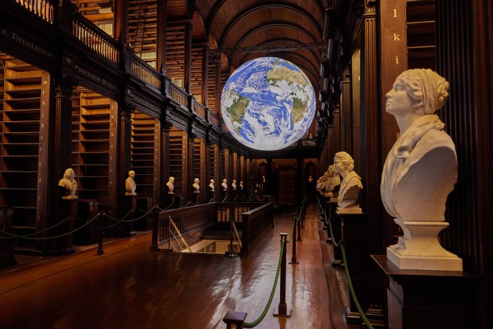 White sculptures in a room with dark oak brown wood and an illuminated illustration of Earth