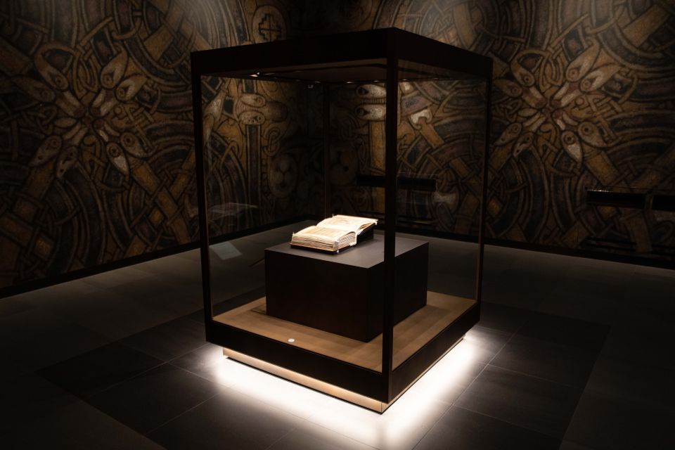 A glass case in a dimly lit room with two pages of the Book of Kells on display.