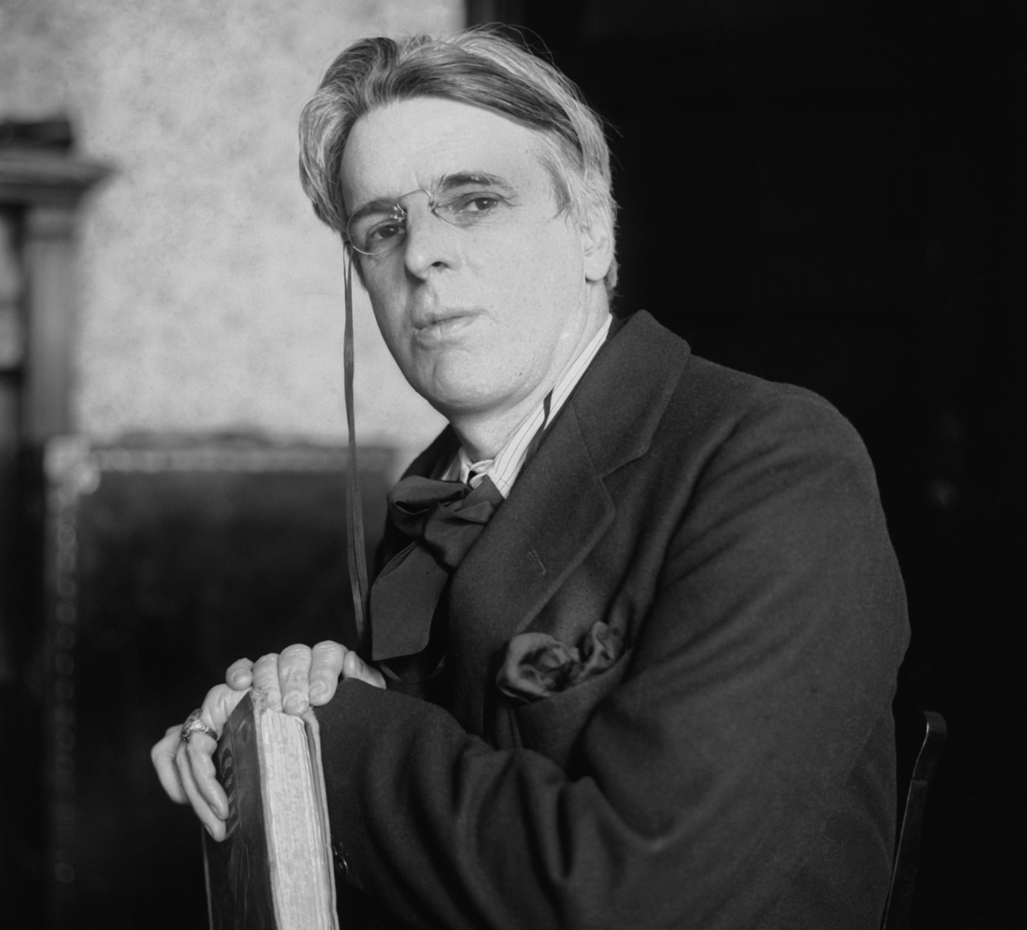 A black and white image of William Butler Yeats holding a book